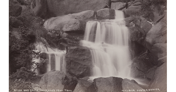 A black-and-white photograph of rushing water tumbling down rocks.