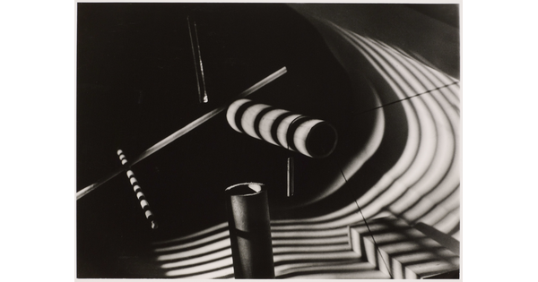 An abstract black-and-white still life of several dowels with striped shadows cast over them.