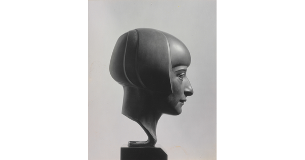 A black-and-white photograph of a bronze bust of a woman in profile with a bobbed haircut.