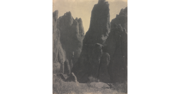 A black-and-white photograph of large hoodoos, or vertical spires of rock.