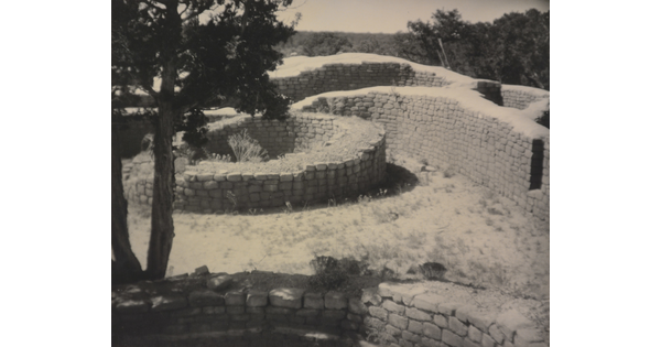 A sepia-toned photograph of open-topped brick structures forming round and curved enclosures.