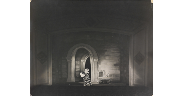 A black-and-white photograph of a woman performing on a stage.