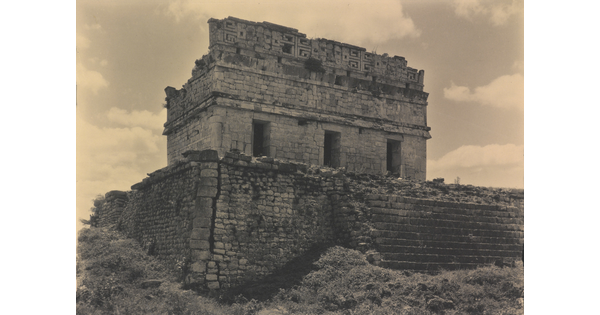 A sepia-toned photograph of a ruined stone temple in at the top of a crumbling stone staircase.