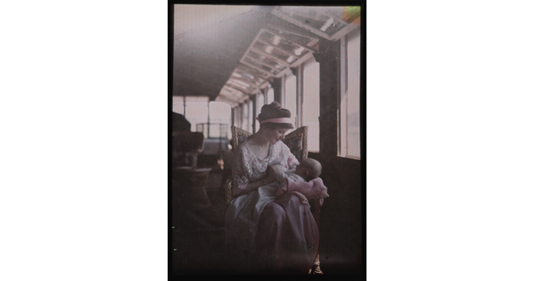 A color image of a seated White woman looking lovingly at an infant in her arms.