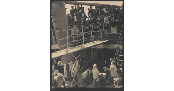 A black-and-white photograph of people outside on two decks of a crowded ship.