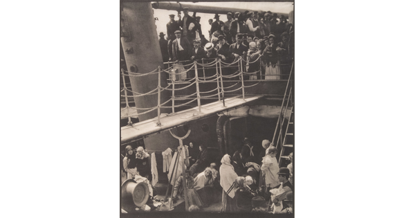 A black-and-white photograph of people outside on two decks of a crowded ship.