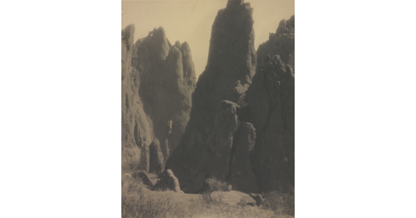 A black-and-white photograph of large hoodoos, or vertical spires of rock.