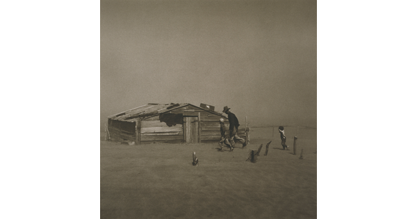 A black-and-white photograph of a man and two children walking through a dust storm by a dilapidated structure.
