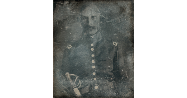 A dark, heavily scratched black-and-white photograph of a White man with a moustache, wearing military regalia and a sword.