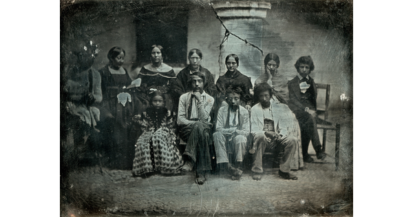 A black-and-white formal group portrait photograph of a medium-skinned group of adults and children.