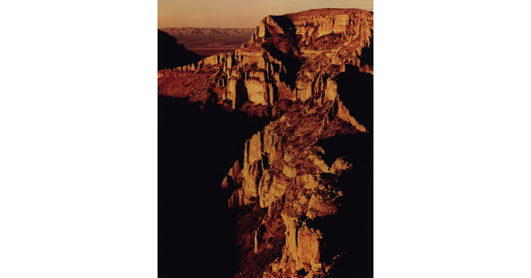 A color photograph of a rocky canyon landscape, the light reflecting off some of the cliff faces.