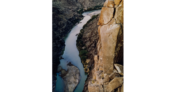 A color photograph taken from above of a river running through a canyon below steep rocky cliffs.
