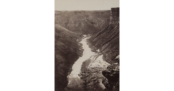 A black-and-white photograph, taken from a high elevation, of a river surrounded by cliffs and steep hillsides.