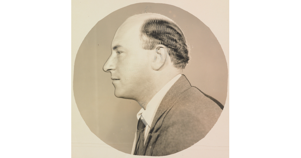 A circular black-and-white photograph of a balding White man in profile.