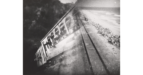 A black-and-white photograph of a train car overlayed with a photograph of train tracks.