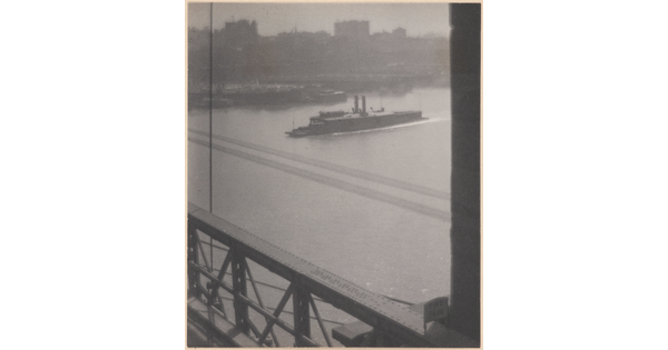 A black-and-white photograph of a boat preparing to cross under a bridge as viewed from the bridge.