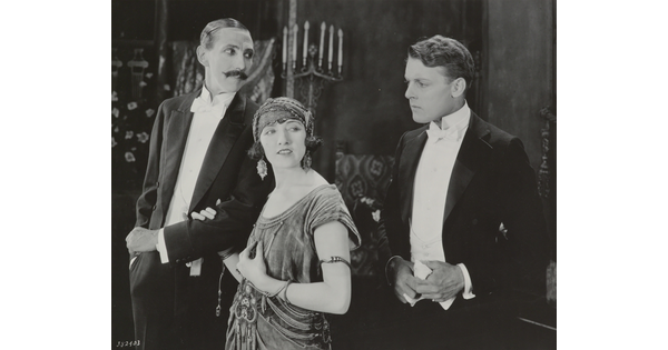 A black-and-white photograph of a White woman and two White men, all dressed in formal attire and looking in different directions.