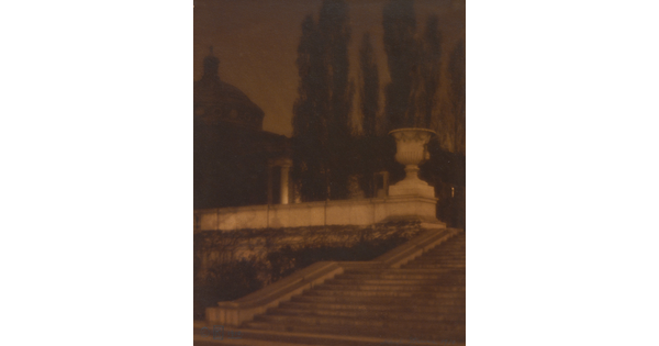 A sepia-toned photograph of a set of stone stairs leading to a plaza with a large urn, a domed building, and tall thin trees.