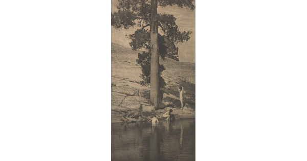 A sepia-toned photograph of three nude women bathing in a pool of water under a large tree.