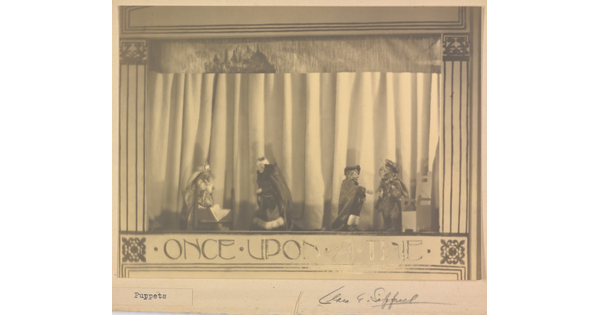 A sepia-toned photograph of a puppet stage with four puppets and the words "Once Upon a Time" written at the bottom.