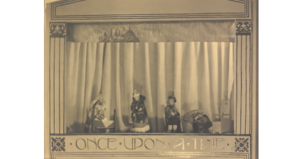 A sepia-toned photograph of a puppet stage with four puppets and the words "Once Upon a Time" written at the bottom.
