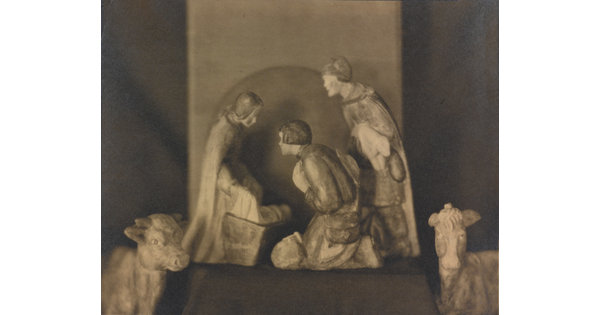 A sepia-toned photograph of human and animal figurines assembled in a nativity scene.