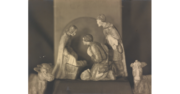 A sepia-toned photograph of human and animal figurines assembled in a nativity scene.
