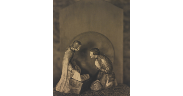 A sepia-toned photograph of human figurines assembled in a nativity scene.