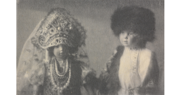A black-and-white photograph of two light-colored dolls wearing Russian imperial clothing.