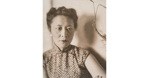 A sepia-toned portrait photograph of a woman with Asian features, her hair pulled up, wearing a top with a geometric design.