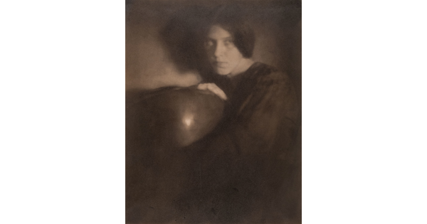 A black-and-white photograph of a White woman in dark clothing holding a bowl.