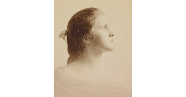 A black-and-white portrait photograph of a White woman in profile, hair pulled back with a bow.