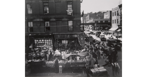 A black-and-white photograph of intersecting city streets crowded with people and vendors for a street market.