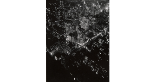 A black-and-white photograph of a bird's eye view of city lights at night.