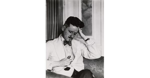 A black-and-white portrait photograph of a seated, nicely dressed White man resting his head on his hand.