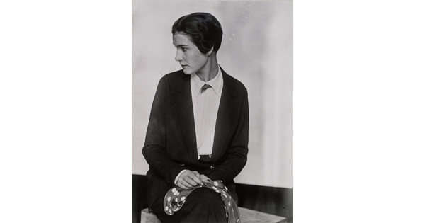 A black-and-white portrait photograph of a seated White woman holding a scarf in her lap with her head turned in profile.