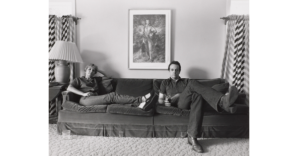 A black-and-white photograph of a White woman and man seated at opposite ends of a couch.