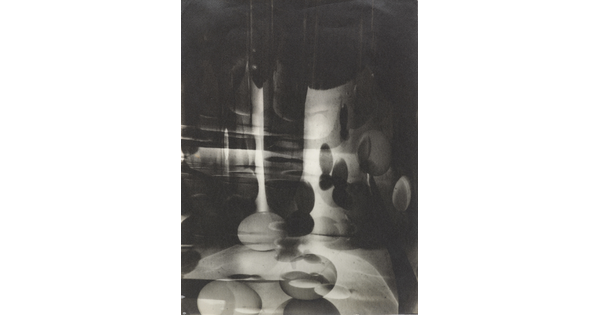 A black-and-white photograph of abstracted egg shapes layered and reflected on top of one another.