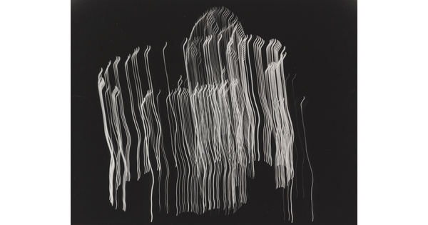 A black-and-white photograph of vertical streaks of white light layered in a circular shape on a black background.
