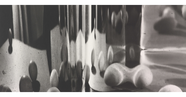 An abstract black-and-white photograph of blurred orb shapes reflected on a curved surface.