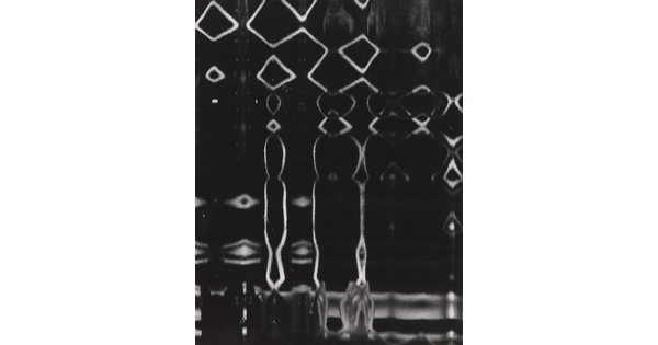An abstract black-and-white photograph of white lines making a pattern of diamonds and drip-like shapes on a black background.