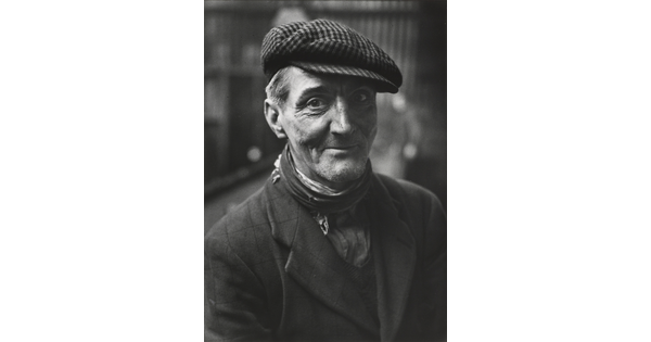 A black-and-white portrait photograph of a smiling man looking at the camera.