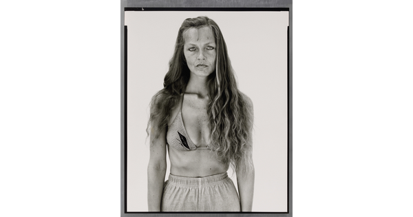 A black-and-white portrait photograph of a White woman with long hair, wearing a bikini top and athletic shorts.