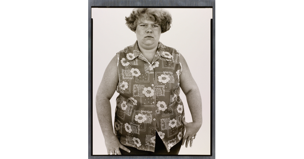 A black-and-white portrait photograph of a White woman with short hair in a sleeveless button-down shirt with a floral pattern.