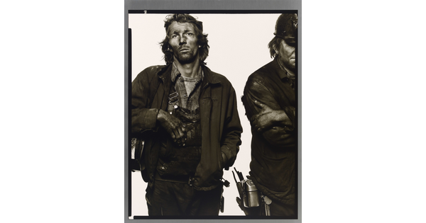 A black-and-white portrait photograph of two men, the one on the right is only half in the frame, in dirty work clothes covered in dark coal dust.