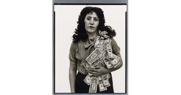 A black-and-white portrait photograph of a White woman with a sash of flowers and dollar bills flowing over her shoulder.