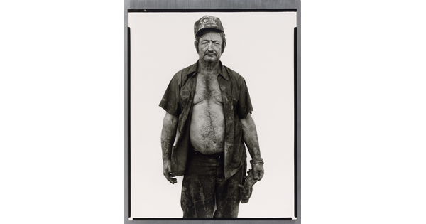 A black-and-white portrait photograph of a middle-aged White man wearing a baseball cap, a dirty, open button-down shirt, and a work glove on one hand.