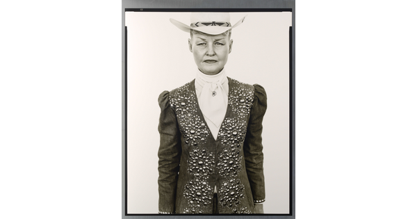 A black-and-white portrait photograph of a White woman wearing a white cowboy hat and a jacket embellished with rhinestones in a floral pattern over a white blouse.