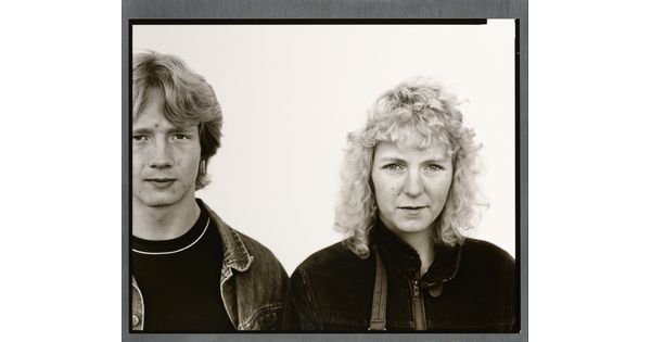 A black-and-white portrait photograph of a young White man with shaggy hair wearing a jean jacket, and a young White woman with curly hair wearing a corduroy jacket.