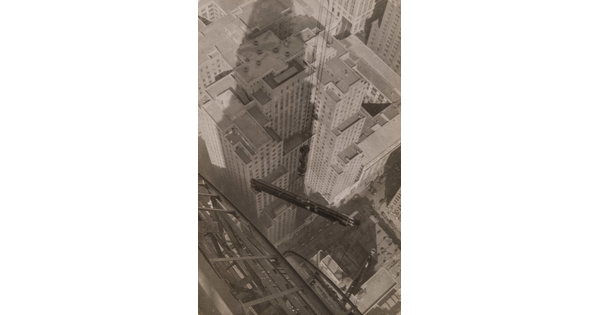 A black-and-white photograph looking from atop a skyscraper as a steel beam suspended by wire cables is lifted over a city.
